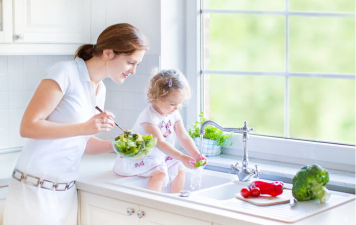 mother and daughter rinsing lettuce in the kitchen