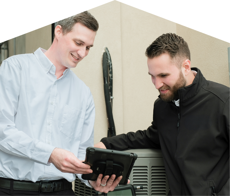 A Francis technician in a white shirt shows service details on a tablet to a smiling client in a black jacket, standing beside an AC unit outside a beige building.