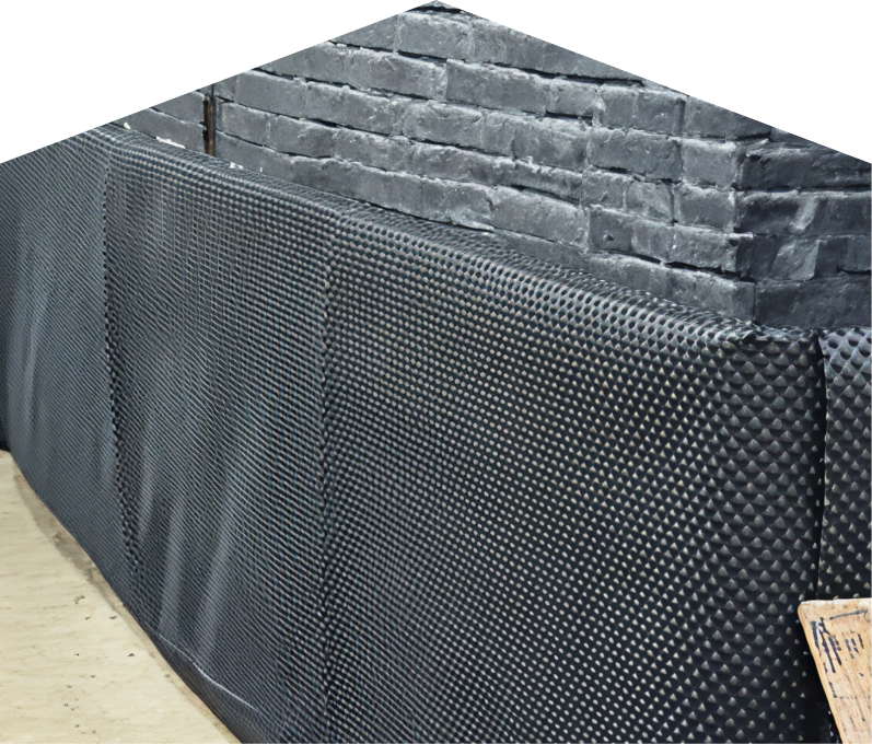 Exterior basement waterproofing completed by Francis, showing a sealed foundation wall with dimpled waterproof membrane partially installed on a brick surface, preventing moisture infiltration. Exterior basement waterproofing completed by Francis, showing a sealed foundation wall with dimpled waterproof membrane partially installed on a brick surface, preventing moisture infiltration.