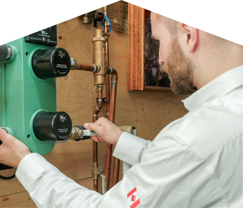 Francis HVAC specialist performing boiler installation, securing a valve on a new hydronic heating system with copper piping and a green circulation pump mounted on a wooden wall. Francis HVAC specialist performing boiler installation, securing a valve on a new hydronic heating system with copper piping and a green circulation pump mounted on a wooden wall.