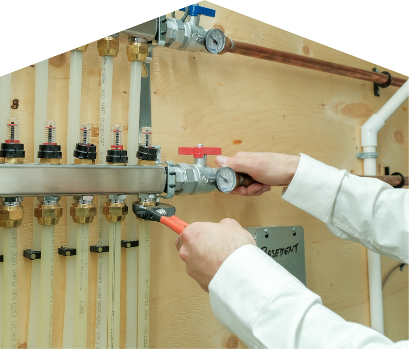Francis HVAC specialist performing boiler repair, adjusting internal components of a residential unit with visible copper piping and control wiring.