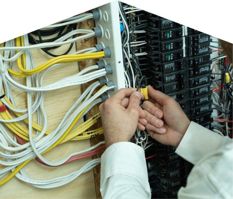 Francis service personnel working on electrical installations, connecting wires inside a residential breaker panel with neatly arranged colored cables on a plywood backing. Francis service personnel working on electrical installations, connecting wires inside a residential breaker panel with neatly arranged colored cables on a plywood backing.