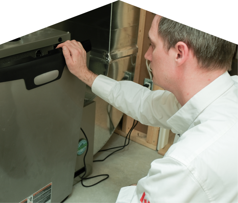 Francis HVAC professional installing a new furnace unit, aligning the front panel with surrounding ductwork and wiring in a residential utility space.