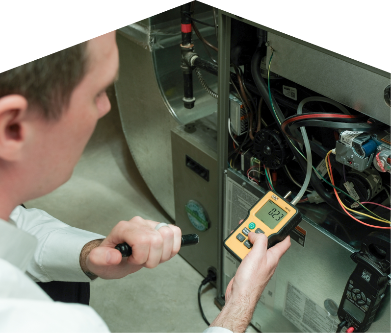 Francis HVAC specialist performing furnace repair on a heating system, using a digital manometer to check pressure. Francis HVAC specialist performing furnace repair on a heating sy