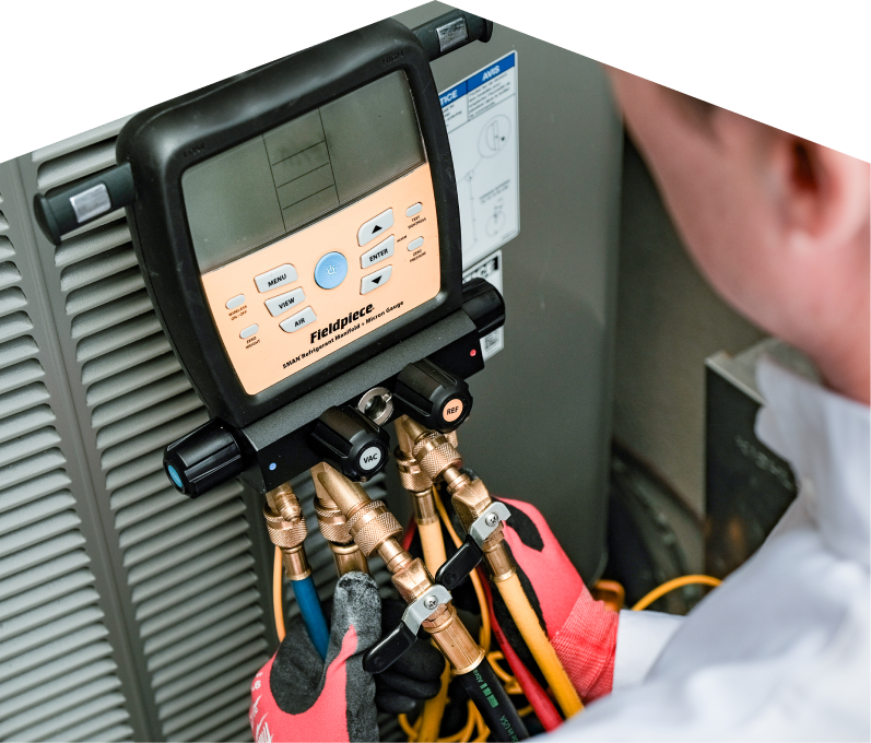 A Francis home service crew member uses a digital manifold gauge to check refrigerant levels on an HVAC unit for service.
