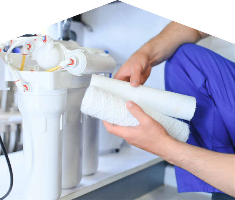 Francis water filtration specialist replacing filter cartridges on a reverse osmosis water system installed under a sink.