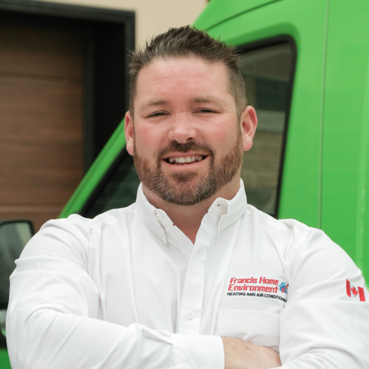 Francis Home Environment technician standing by our famous green trucks in a residential neighbourhood.